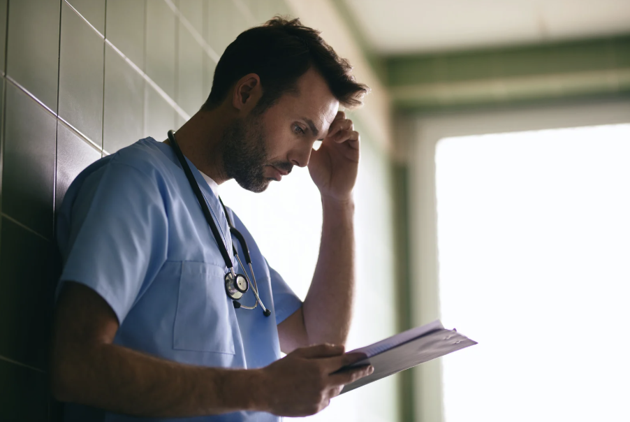 Médico preocupado com processos e judicialização médica, analisando documentos e buscando seguro de responsabilidade civil.